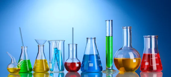 Different laboratory glassware with color liquid and with reflection on blu — Stock Photo, Image