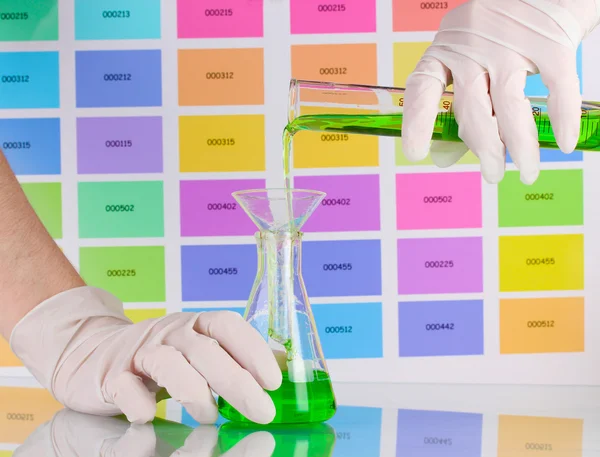 Laborkolben und Röhrchen mit grüner Flüssigkeit in den Händen des Wissenschaftlers auf co — Stockfoto