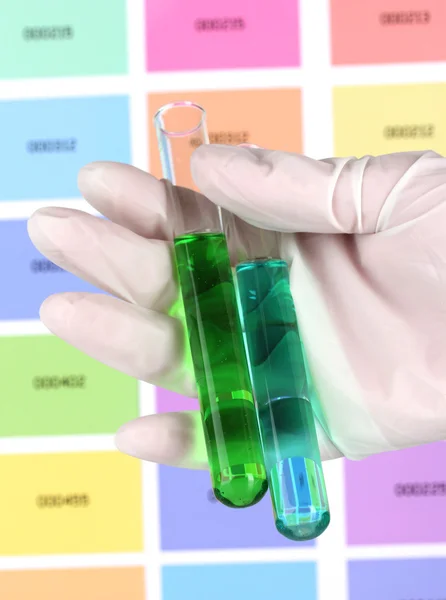 Dois tubos com líquido verde e azul na mão em amostras de cor fundo — Fotografia de Stock