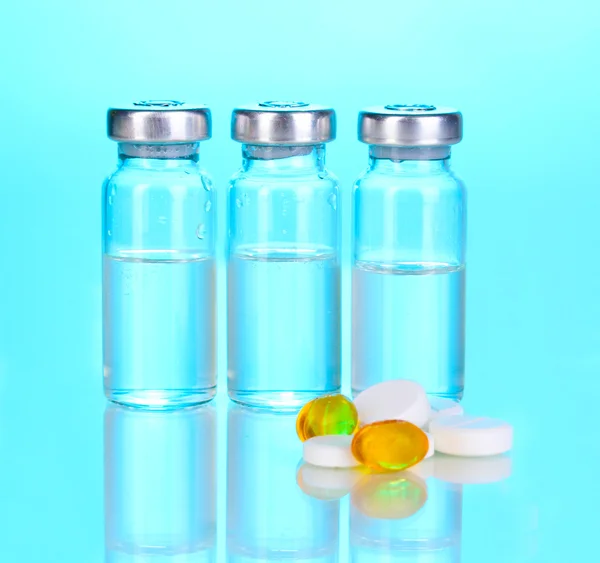 Comprimidos e ampolas sobre fundo azul — Fotografia de Stock
