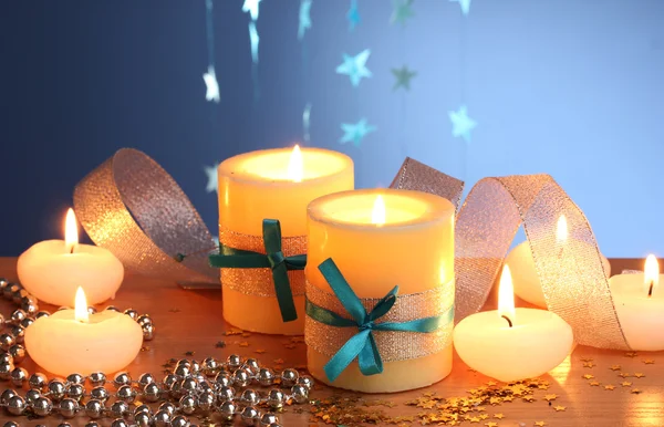 Mooie kaarsen, geschenken en decor op houten tafel op blauwe achtergrond — Stockfoto
