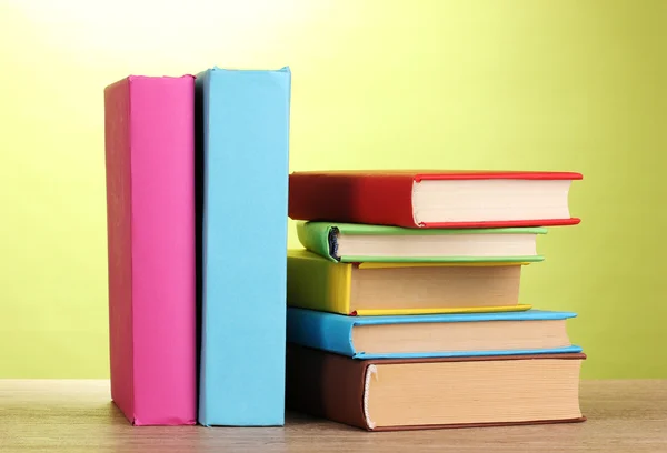Stapel boeken op houten tafel op groene achtergrond — Stockfoto