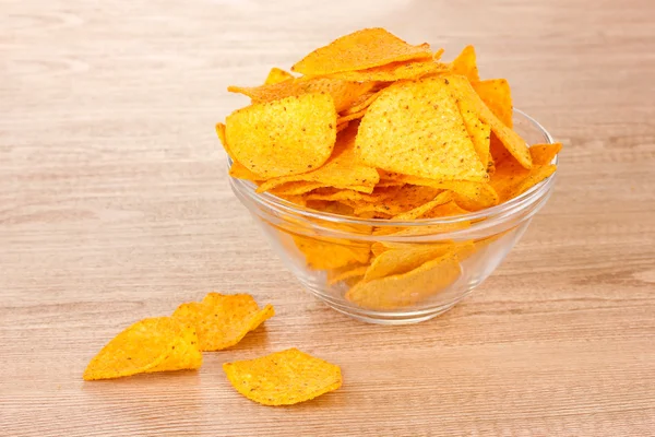 Smakelijke potato chips in transparante kom op houten tafel — Stockfoto