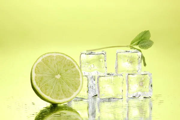 Hoja de menta fresca y cubitos de hielo con gotitas y lima sobre fondo verde —  Fotos de Stock