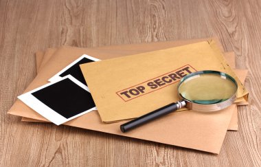 Envelopes with top secret stamp with photo papers and magnifying glass on w clipart