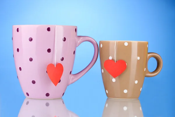 Two cups and tea bags with red heart-shaped label on blue background — Stock Photo, Image