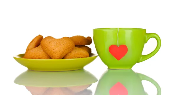 Tazza verde con bustina di tè e biscotti a forma di cuore su piastra verde isolato su — Foto Stock