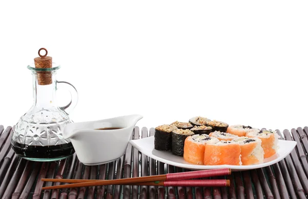 Lekkere broodjes geserveerd op wit bord met stokjes en soja saus op bamboe m — Stockfoto
