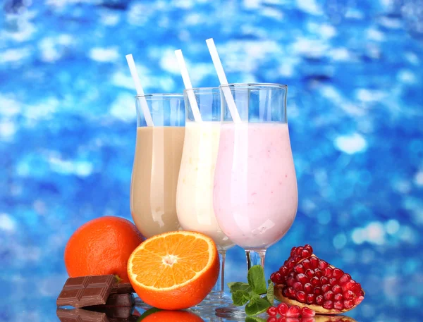 Batidos de leite com frutas e chocolate no fundo azul — Fotografia de Stock