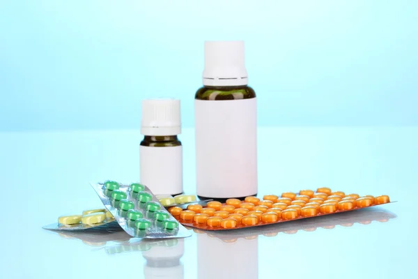 Medical bottles and tablets on blue background — Stock Photo, Image