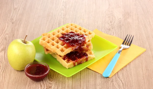 Waffles saborosos com geléia na placa no fundo de madeira — Fotografia de Stock