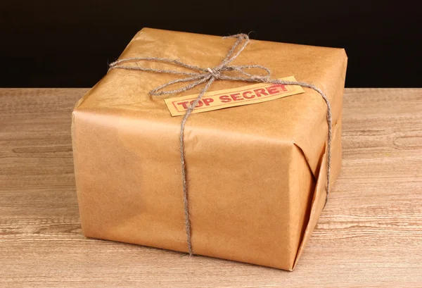 stock image Parcel with top secret stamp on wooden table on brown background