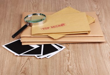 Envelopes with top secret stamp with photo papers and magnifying glass on w clipart