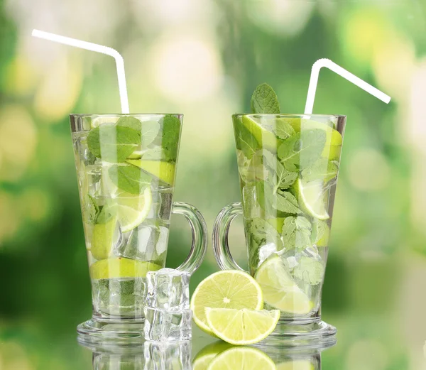 Стаканы коктейля с лаймом и мятой на зеленом фоне — стоковое фото
