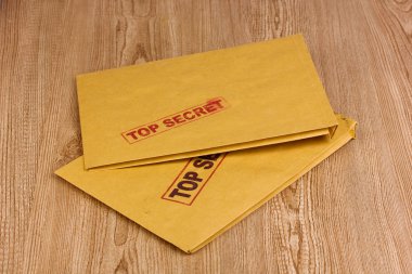 Envelopes with top secret stamp on wooden background clipart