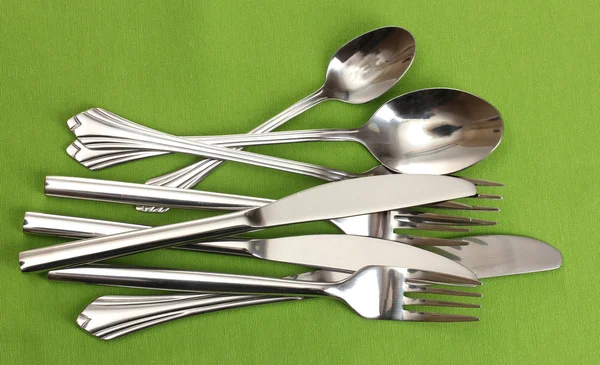 Tenedores, cucharas y cuchillos sobre un mantel verde —  Fotos de Stock