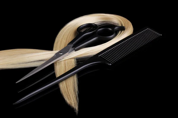 Cabelo loiro brilhante com tesouras de corte de cabelo e pente isolado em preto — Fotografia de Stock