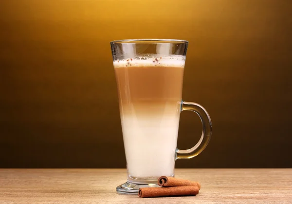 Geurige? offee latte in glas cup en kaneel op houten tafel op bruin ba — Stockfoto
