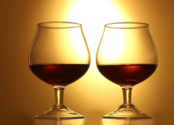 Twee glazen van cognac op gele achtergrond — Stockfoto