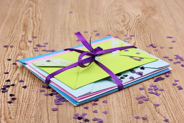 Bando de envelopes de cores com fita e confete em fundo de madeira — Fotografia de Stock