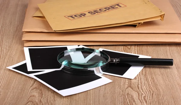 Φάκελοι με κορυφαίο μυστικό σφραγίδα με φωτογραφικά χαρτιά και μεγεθυντικό φακό σε w — Φωτογραφία Αρχείου