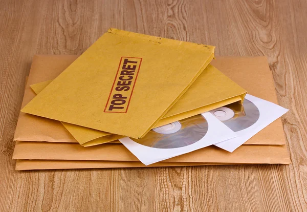 Envelopes com selo ultra secreto com discos de CD sobre fundo de madeira — Fotografia de Stock