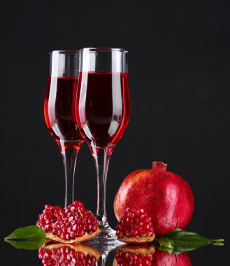 Ripe pomergranate and glasses of wine on black background clipart