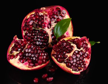 Ripe pomegranate fruit with leaves on black background clipart