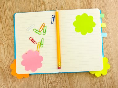 Open note book with stickies and pencil on wooden background clipart