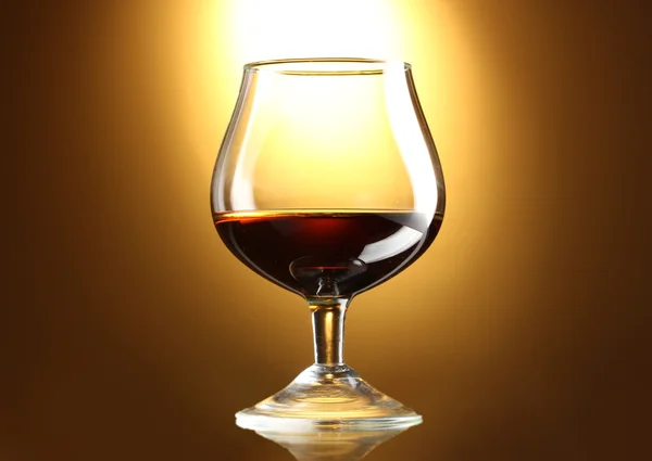 Glas Cognac auf gelbem Hintergrund — Stockfoto