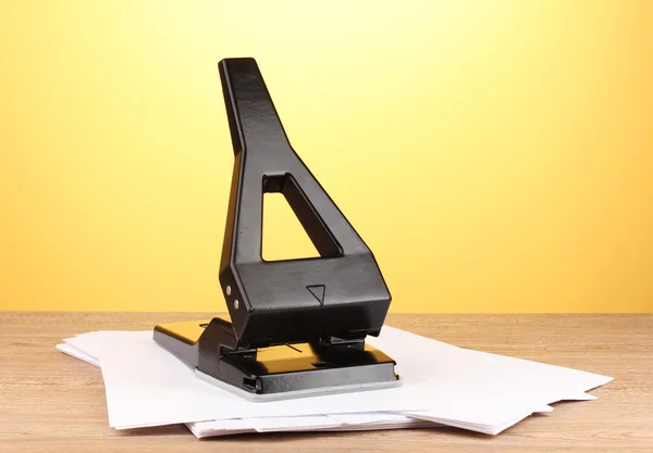 Black office hole punch with paper on yellow background — Stock Photo, Image