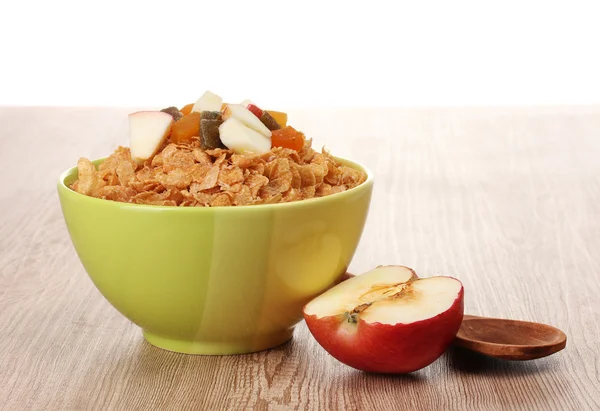 Tasty cornflakes in bowl with dried fruits and apple on wooden table — Stock Photo, Image