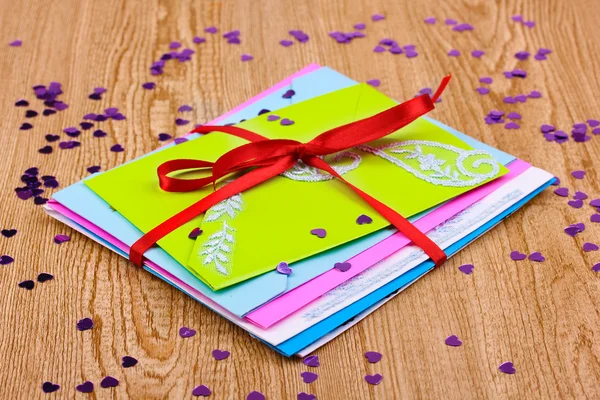 Bando de envelopes de cores com fita e confete em fundo de madeira — Fotografia de Stock