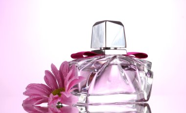 Women's perfume in beautiful bottle and flower on pink background clipart