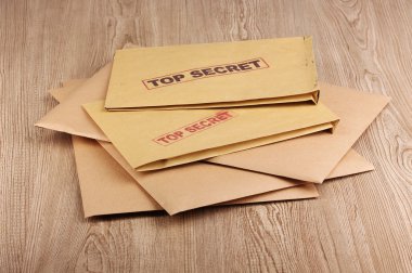 Envelopes with top secret stamp on wooden background clipart