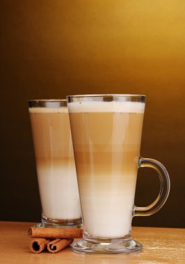 Güzel kokulu? offee latte cam Kupası ve tarçın kahverengi ba üzerinde ahşap tablo