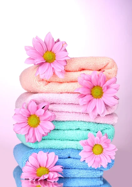 Ručníky a krásné květiny na růžovém pozadí — Stock fotografie