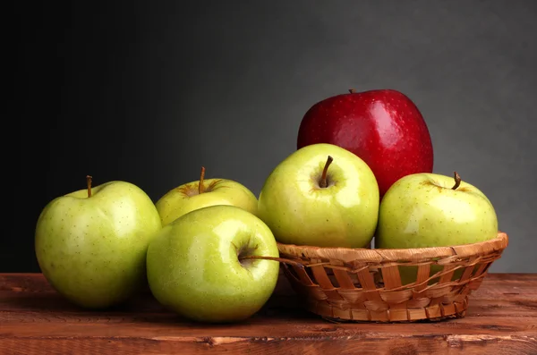Saftige süße Äpfel im Korb auf Holztisch auf grauem Hintergrund — Stockfoto