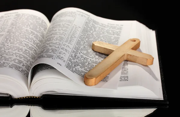 Biblia russa e cruz de madeira sobre fundo preto — Fotografia de Stock