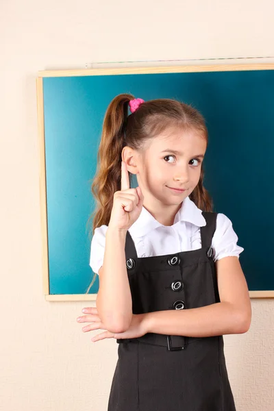 漂亮的小女孩站在教室里的黑板旁边 — 图库照片