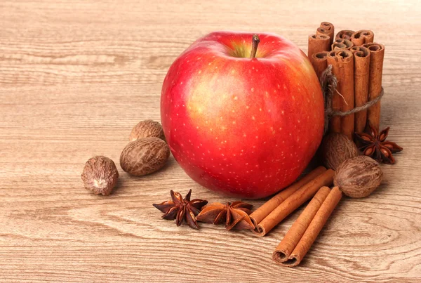 Kaneelstokjes, rode appel, nootmuskaat en anijs op houten tafel — Stockfoto