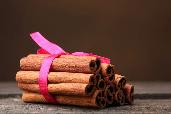 Bâtonnets de cannelle sur table en bois sur fond brun — Photo