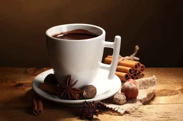 Xícara de chocolate quente, paus de canela, nozes e chocolate na mesa de madeira o — Fotografia de Stock