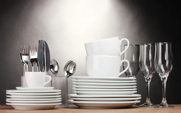 清洁板、 眼镜、 杯子和灰色的背景上的木桌上的餐具 — 图库照片