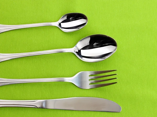 Forchetta, cucchiaio e coltello su una tovaglia verde — Foto Stock