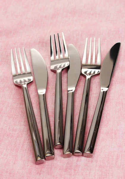 Tenedores y cuchillos sobre un mantel rosa —  Fotos de Stock