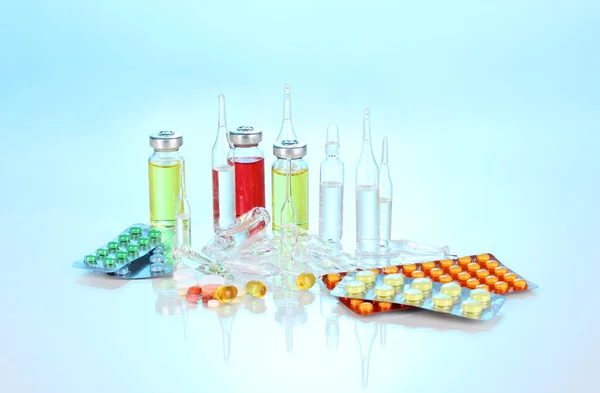 Tabletter och ampuller på blå bakgrund — Stockfoto