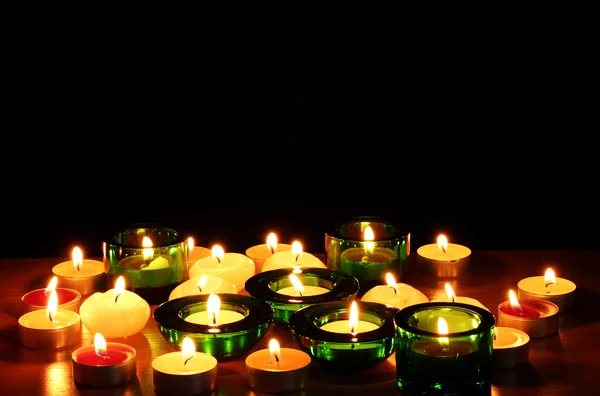 Piękne świece i wystrój na drewnianym stole na czarnym tle — Zdjęcie stockowe