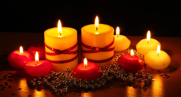 Hermosas velas y decoración en mesa de madera sobre fondo negro —  Fotos de Stock