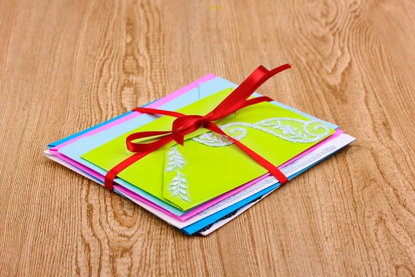 Куча цветных конвертов с лентой на деревянном фоне — стоковое фото